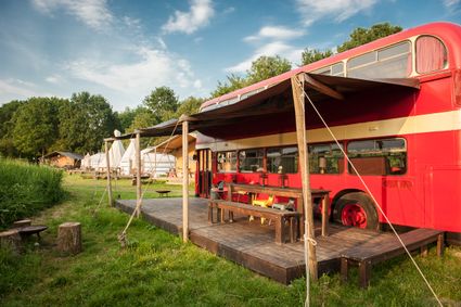 Een rode oude Engelse dubbeldekbus die is omgebouwd tot slaapaccomodatie.