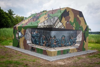 Een betonnen groepsschuilplaats is beschilderd met camouflageprint. Ook kun je hierop zien hoe het was als soldaten zich moesten verschuilen.
