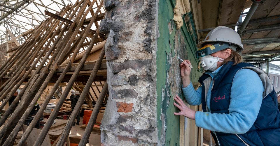 Foto van een restaurateur die de muur van het Huis van Bosch inspecteert.