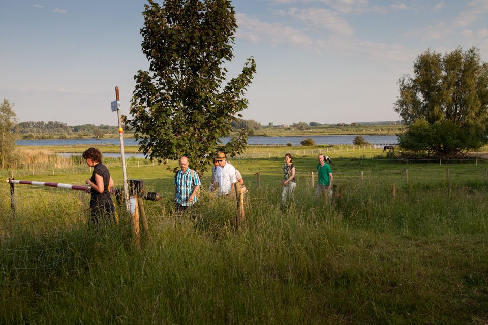 Een groep mensen wandelt over een pad in een groene omgeving.