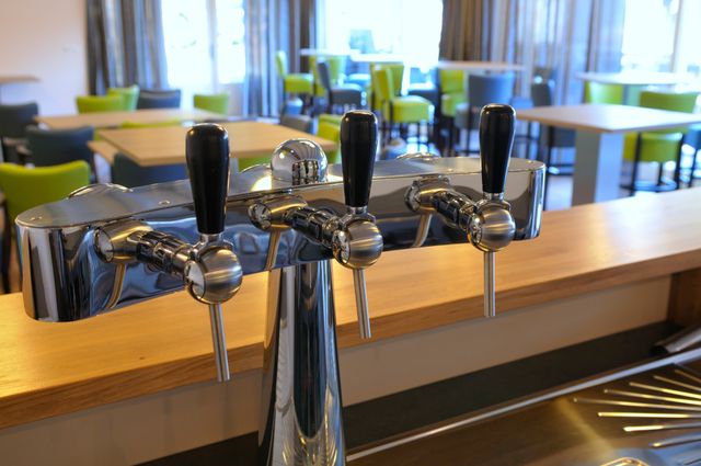 Op de voorgrond een bar met de tap prominent in beeld, op de achtergrond stoelen en tafels. Bij de Strandhoeve in de Noordoostpolder.