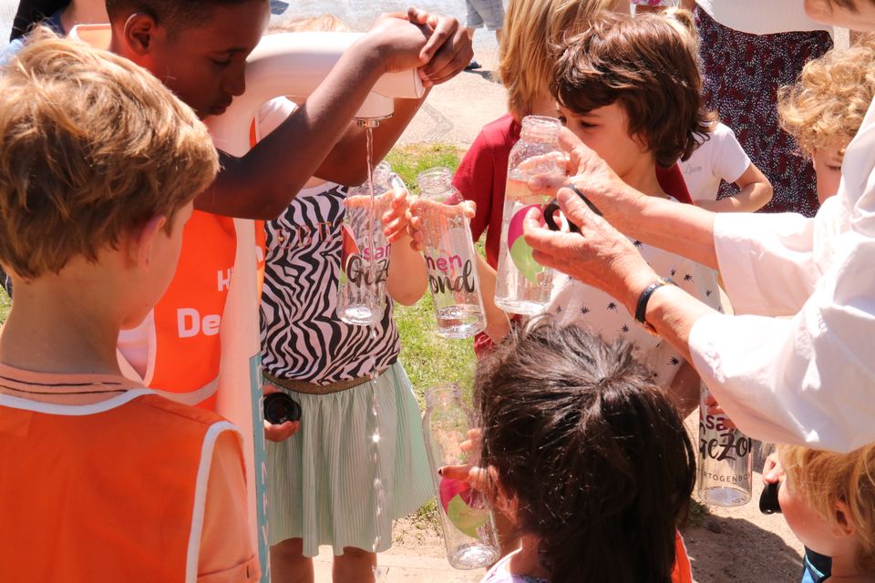 Foto van een watertappunt en kinderen.