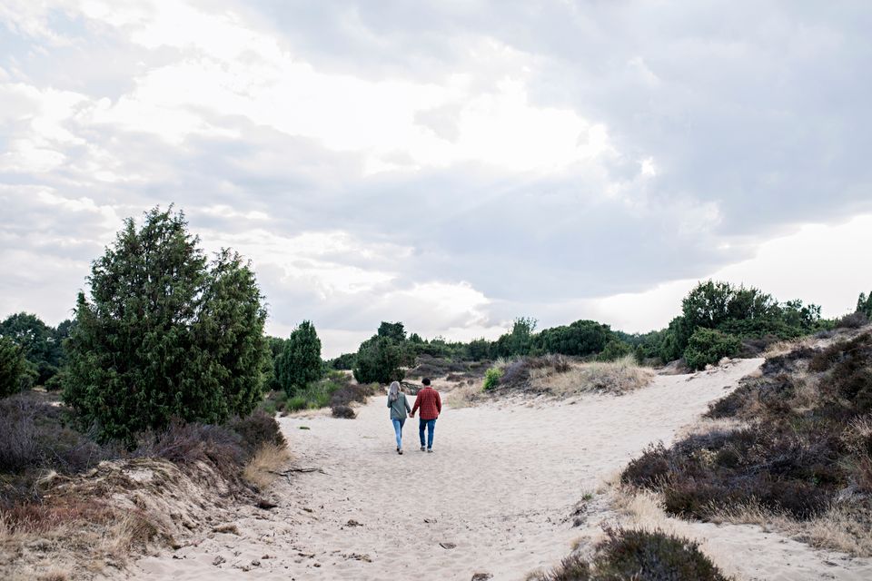 Een stel wandelt over een zandverstuiving en geniet van de natuur in Drenthe.