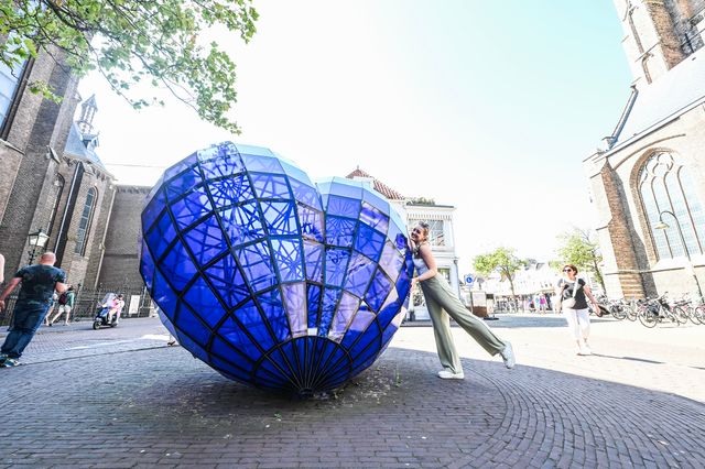 Jonge vrouw omarmt het blauwe hart van Delft
