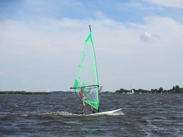 Een windsurfer met een groen zeil op het Alkmaarder- en Uitgeestermeer