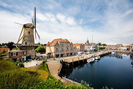 De kade in Willemstad. Je ziet een molen, de haven en huizen.