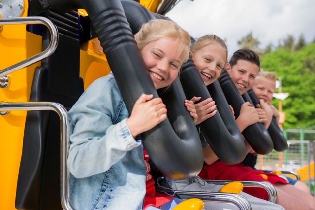 Vier kinderen genieten van een achtbaanrit in een attractiepark.