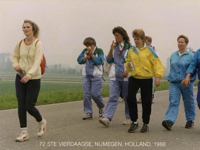 Individuele deelneemsters steken een sigaret op tussen Valburg en Slijk-Ewijk op de eerste dag van de 72e Vierdaagse. De deelneemster links luistert naar de muziekcassette in haar walkman.