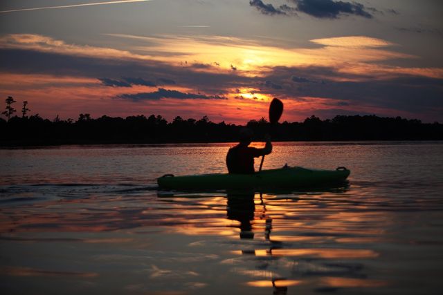 Man is tijdens zonsondergang in zijn kano aan het varen.