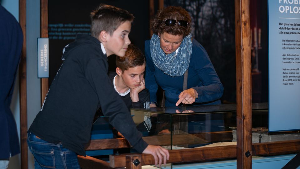 Moeder bekijkt met haar beide zoons een bezienswaardigheid in het museum Proefkolonie Frederiksoord.