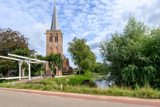 Hervormde kerk aan de Kortenhoefsedijk in Kortenhoef, met wit bruggetje ervoor.