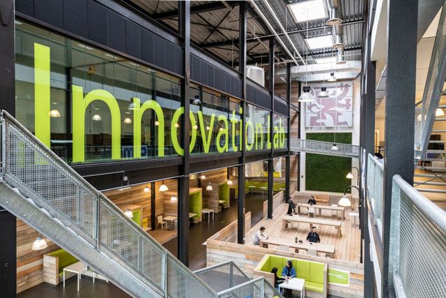 Foto gemaakt vanaf de trap in de Dutch Innovation Factory. Op de foto zie je de tafels waar studenten en bedrijven aan kunnen studeren en werken.