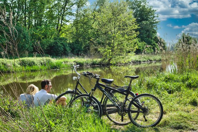 Twee mensen rusten langs het water tijdens een fietstocht