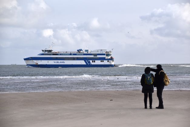 Vlieland Wandelaars op strand met veerboot Doeksen
