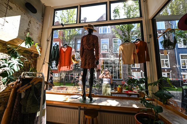 Jongedame bekijkt kleding in een winkeletalage in de zomer in Delft