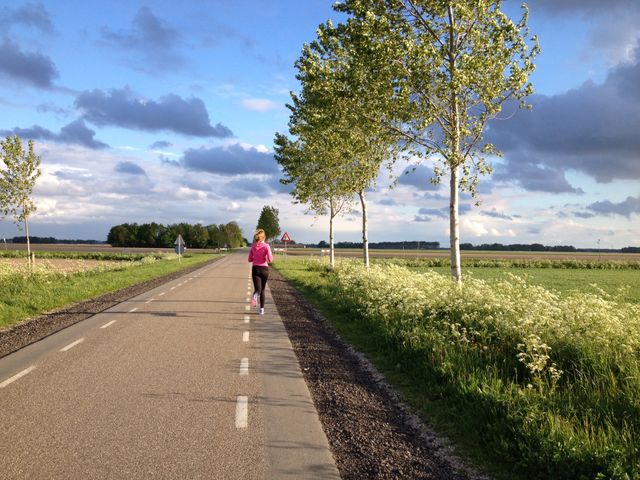 Vrouw loopt hard in het landschap van de Noordoostpolder, Flevoland