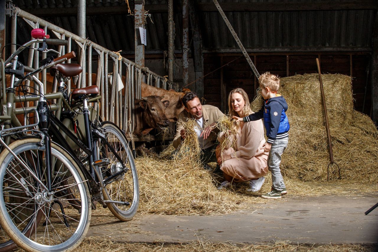 Vader, moeder en kind in de hooi bij de boerderij