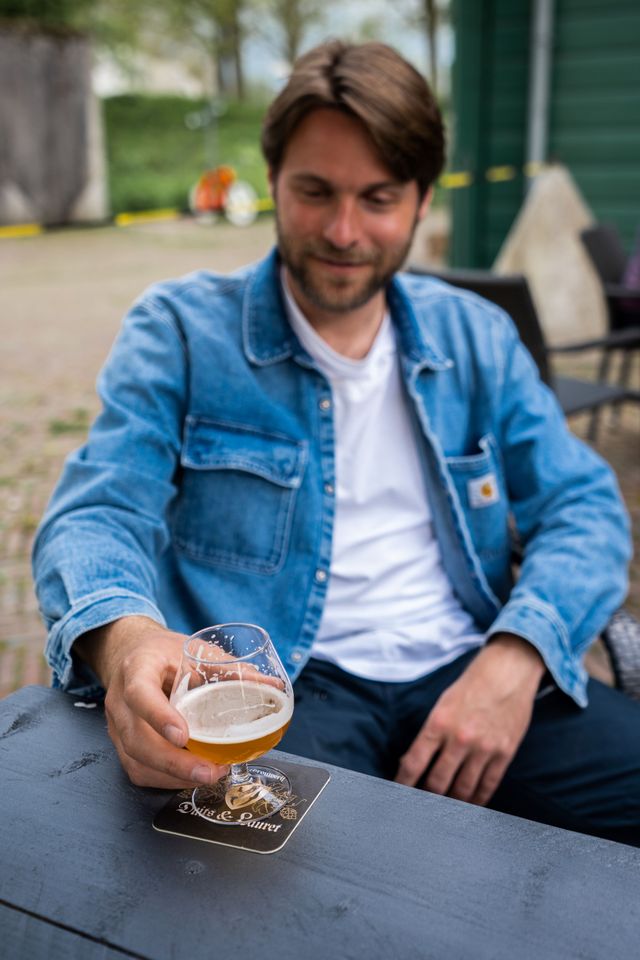 Een jonge man met een glas bier op het terras van Fort Everdingen