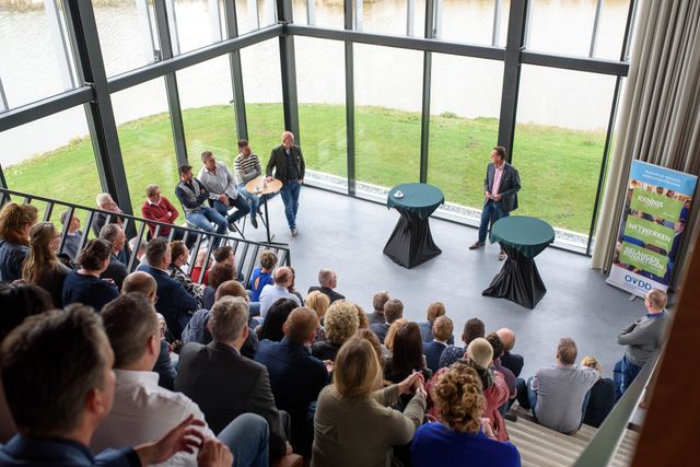 Een presentatie met publiek op een steile tribune tijdens OVDD in Flevoland