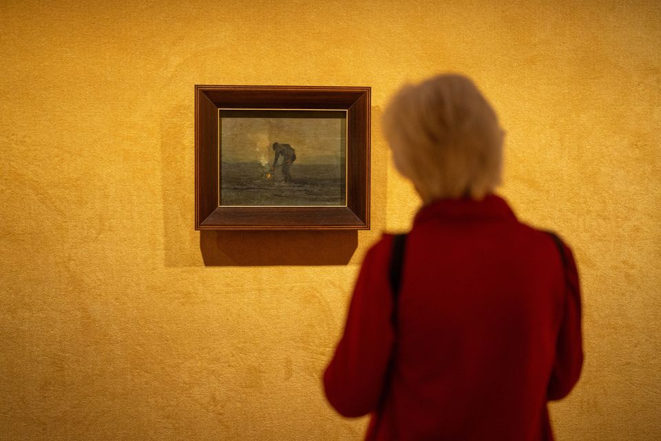 Een vrouw kijkt naar een schilderij in het museum.