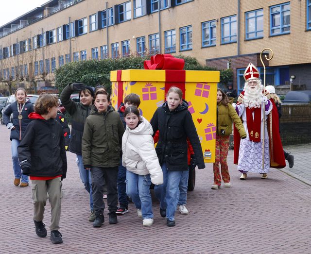 Sinterklaas en de kinderburgemeester en kinderraad brengen het cadeau naar de speeltuin