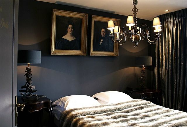 Een foto van een van de kamers in het Damhotel, met boven het bed twee portretten van een man en een vrouw