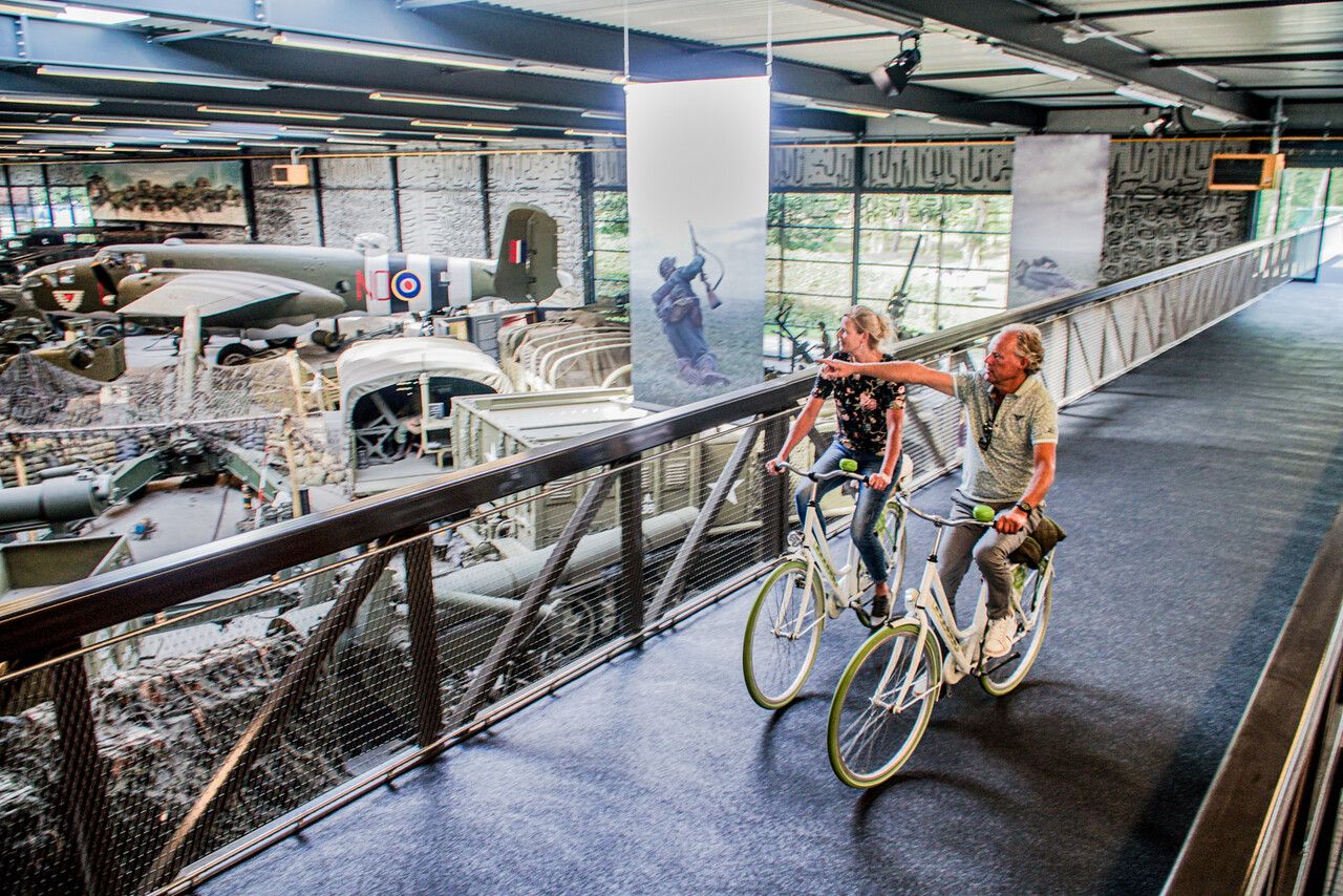 fietsers op een fietsbrug door museum in Overloon